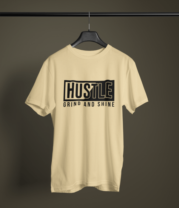 beige color hustle grind and shine graphic printed t-shirt on a hanger