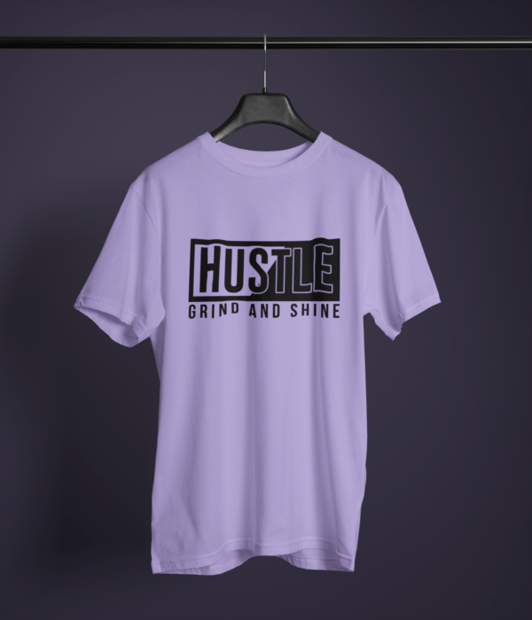 lavender color hustle grind and shine graphic printed t-shirt on a hanger